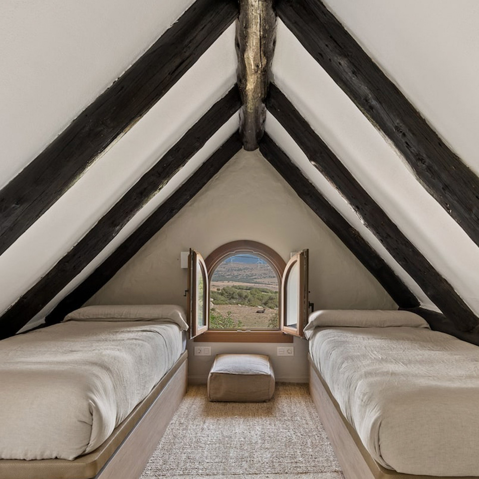 Attic with wooden beams, two beds and mini round window