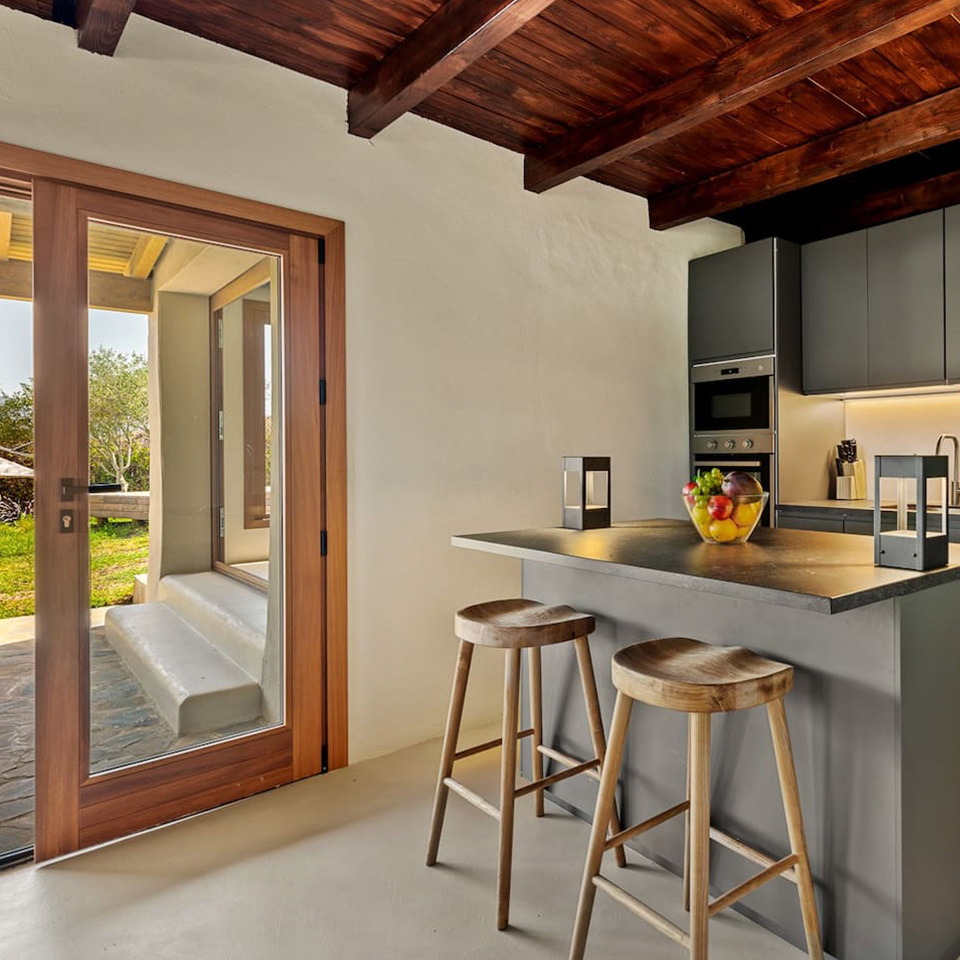 Cocina americana gris con techos de madera y puerta ventanal al jardín