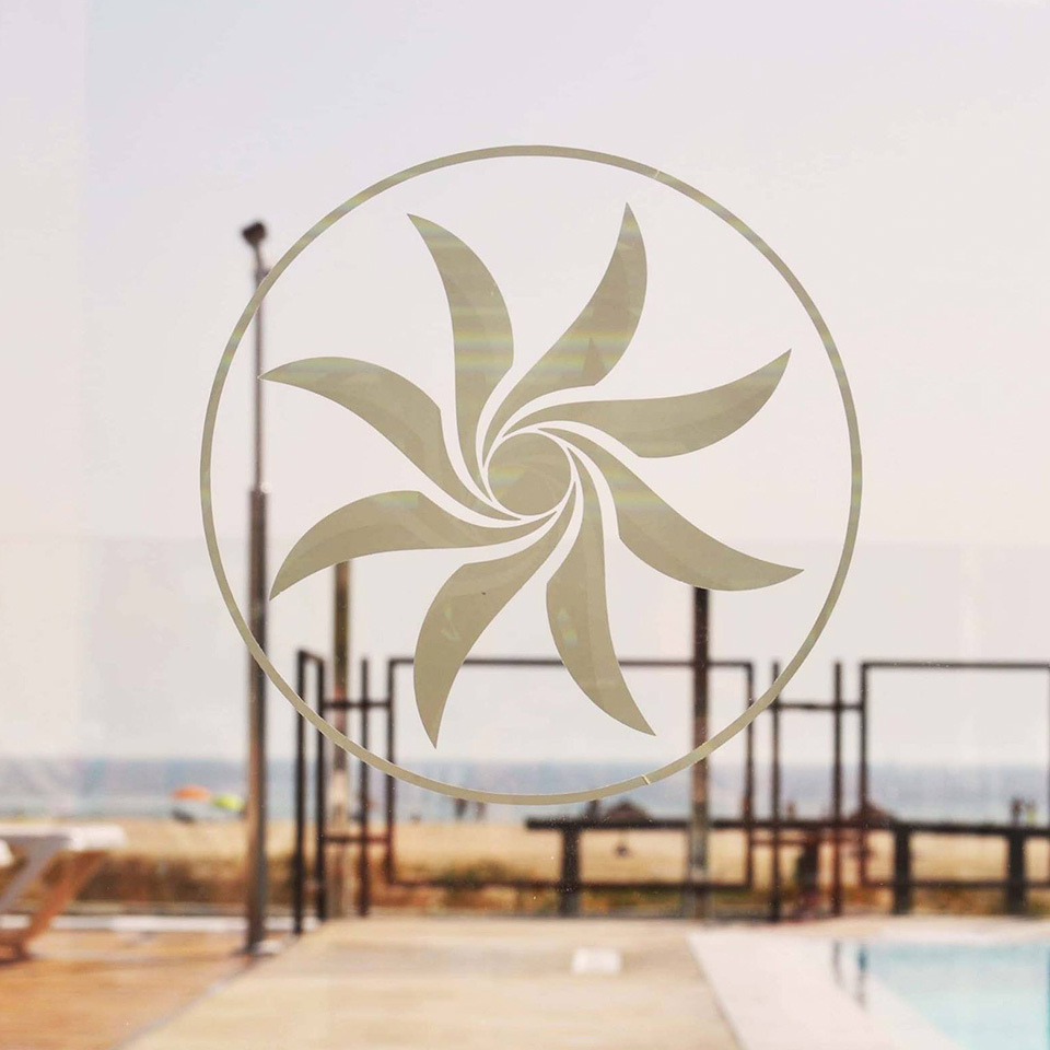 Logotipo del Bar Mandala sobre cristalera transparente con vistas al mar