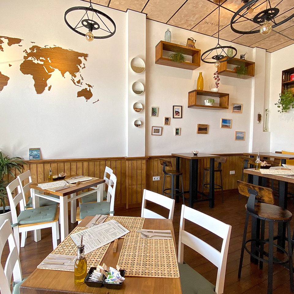 Comedor del Café con paredes decoradas y mesas de distintas maderas